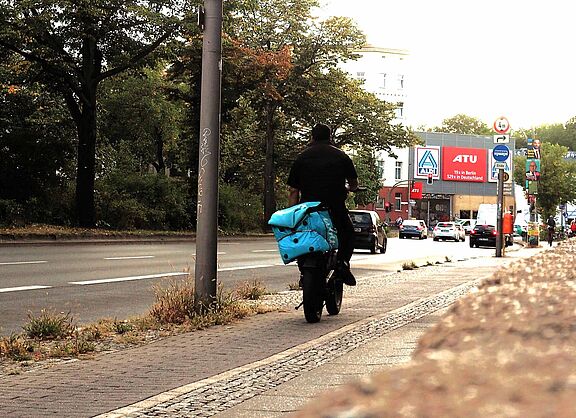 Lieferdienst-Fahrer auf dem Fahrrad transportiert eine Wolt-Transport-Box auf dem Gepäckträger