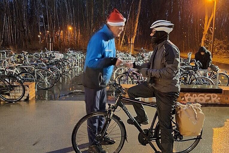 In der Morgendämmerung wird einem Radfahrer die Postkarte mit Zimtstern gegeben