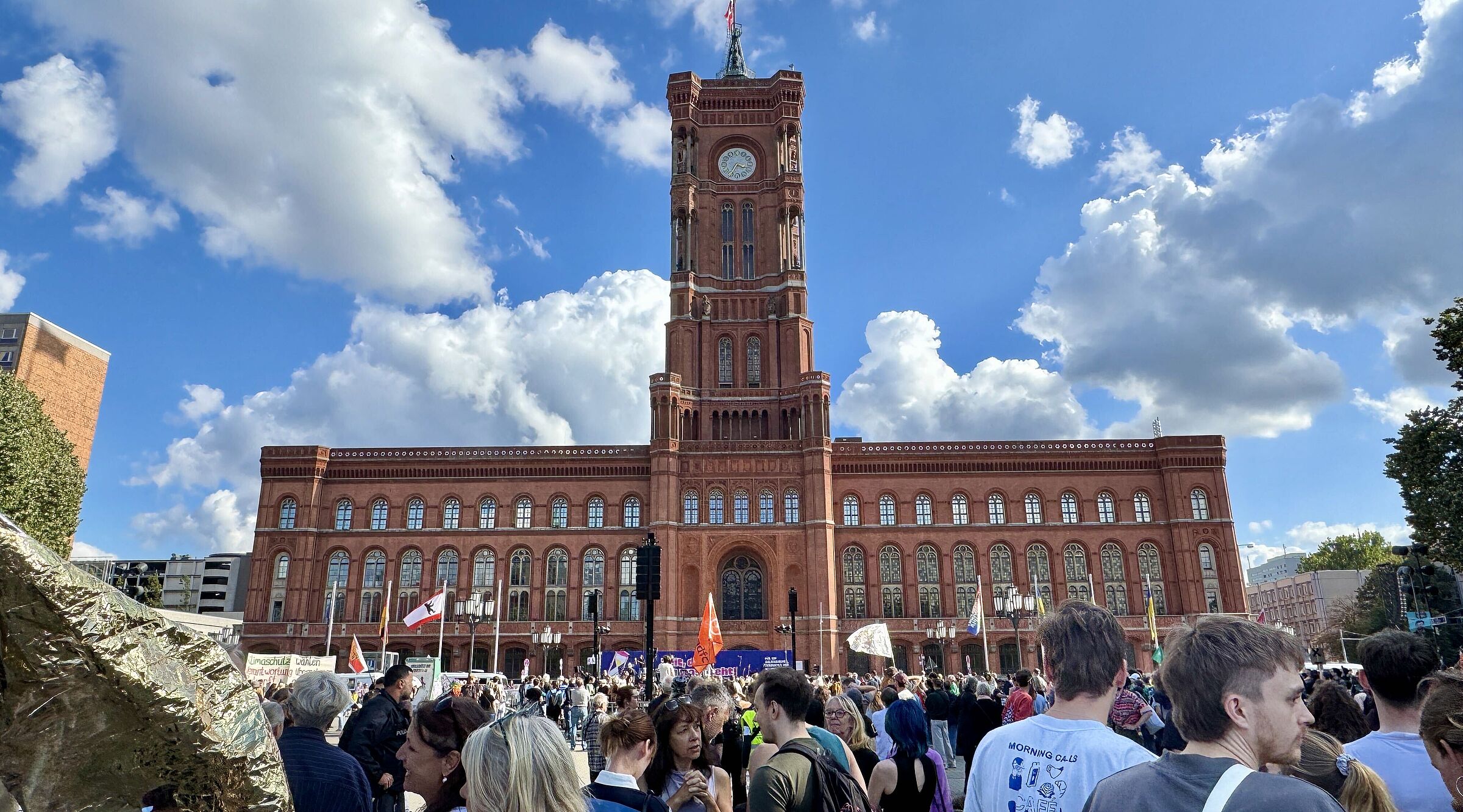 Ein Menschenmenge mit Fahnen und Transparenten vor dem Roten Rathaus Berlin ist zu sehen. 