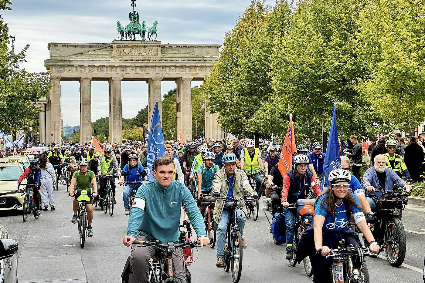 Radfahrende mit Fahnen, im Hintergrund das Brandenburger Tor