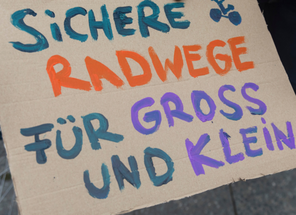 Demo Schild für die Kidical Mass auf dem steht Sichere Radwege für Gross und Klein