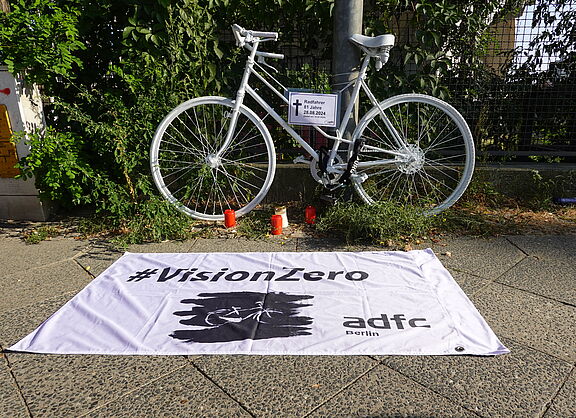 weißes Geisterrad mit Trauerkerzen und weißer Vision Zero Fahne