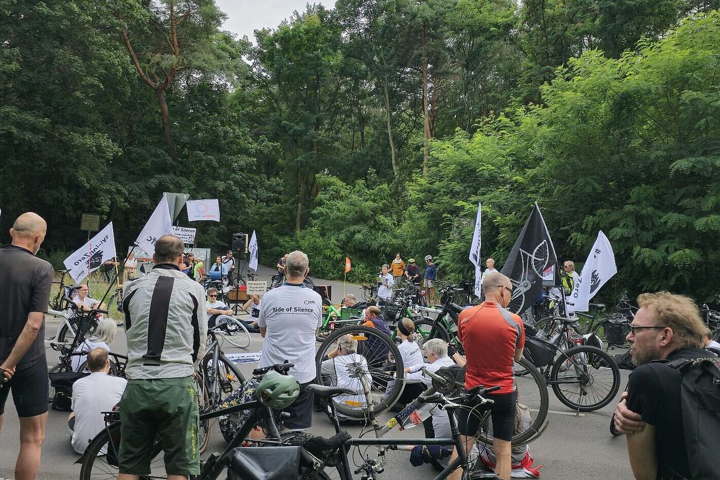 Menschen bei einer Mahnwache mit weißen T-Shirts und Vision Zero Fahnen