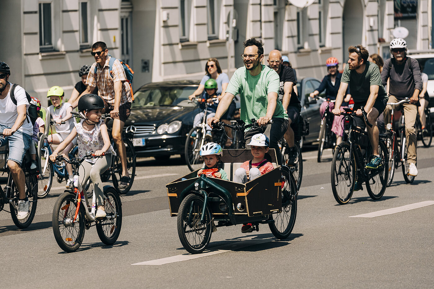 Menschen auf dem Fahrrad und mit Lastenrad auf der Straße