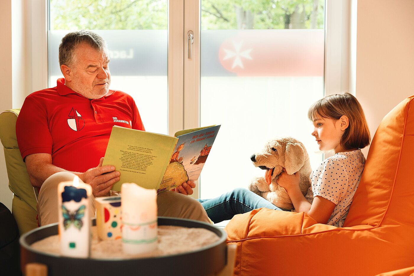 Ein Mann liest einem Mädchen mit einem Stofftier ein Buch vor