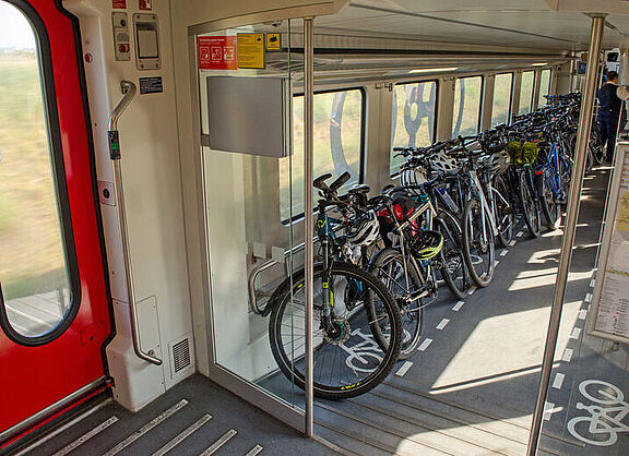 Das Bild zeigt ein Fahrradabteil im Zug mit vielen Rädern
