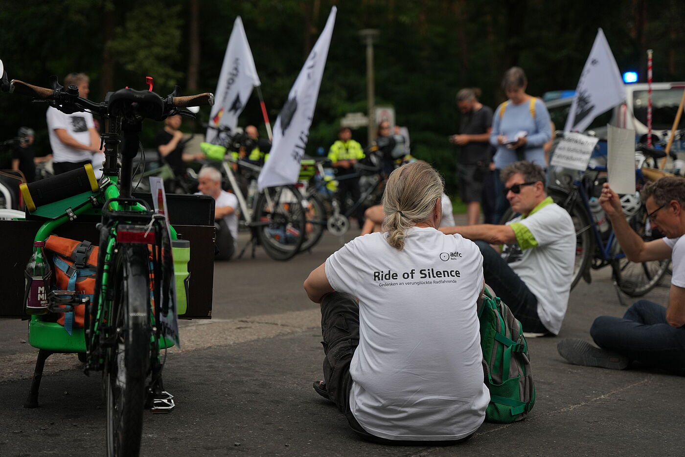 Menschen sitzen bei einer Mahnwache mit weißen T-Shirts auf der Straße