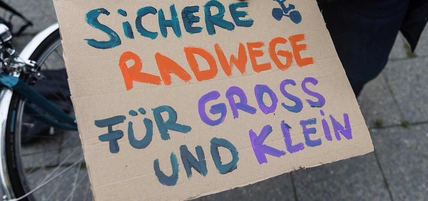 Demo Schild für die Kidical Mass auf dem steht Sichere Radwege für Gross und Klein