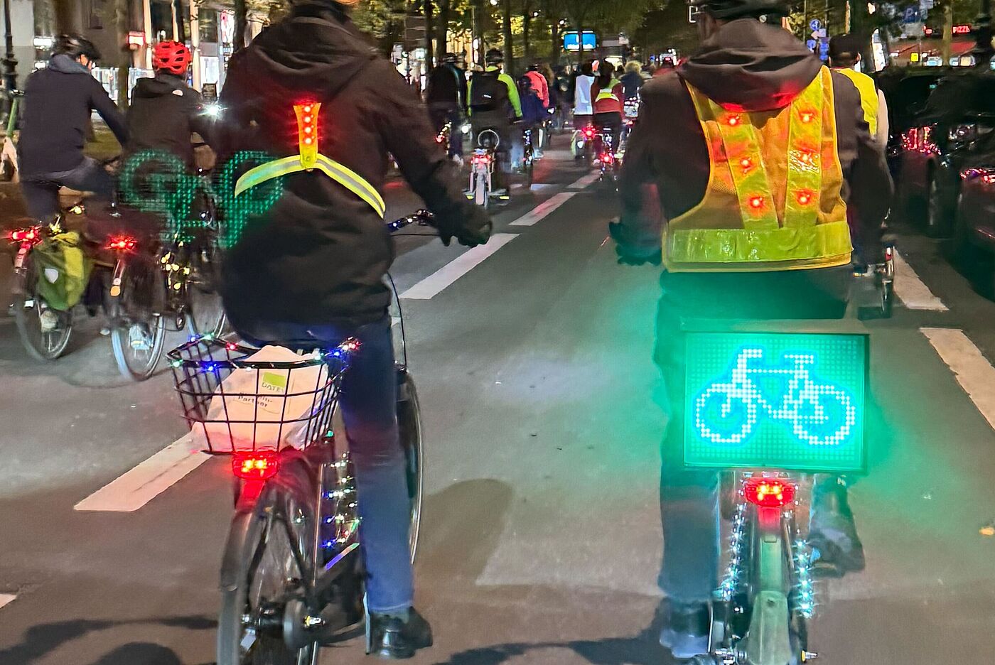 Radfahrende mit Leuchtschild auf Gepäckträger auf dem ein Fahrrad dargestellt ist