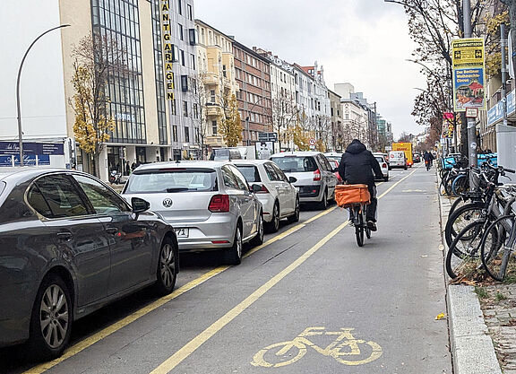 Radweg der links durch parkende Autos abgegrenzt wird