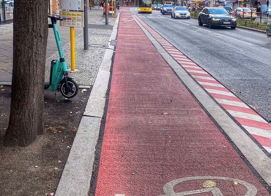 August 2024: Wer in den Bus einsteigen möchte, quert jetzt dieses Stück Radspur an der Bushaltestelle Richard-von-Weizsäcker-Platz. Das Foto zeigt eine rot markierte Radspur an der Bushaltestelle Richard-von-Weizsäcker-Platz. Der Radweg ist dort schmaler als an anderen Stellen.