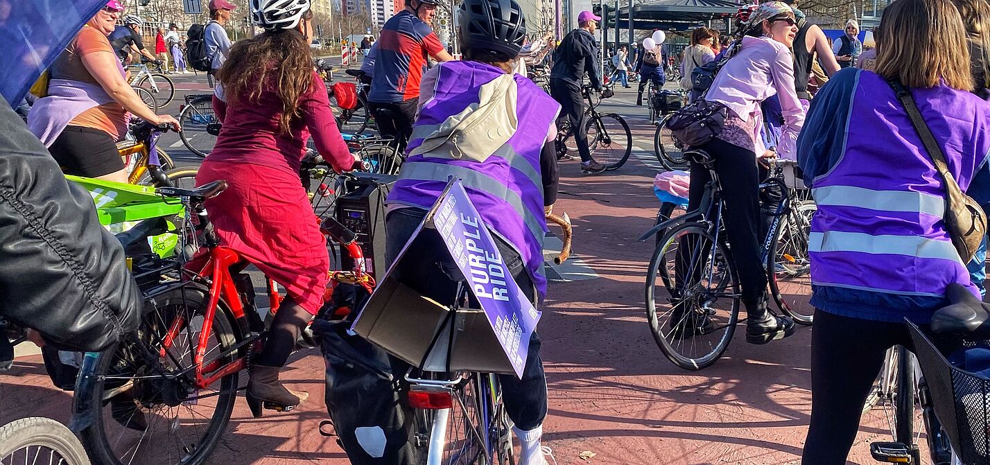 Der ADFC Berlin nimmt am Purple Ride teil. Beim Purple Ride am 08.03.2025 sind mehrere Teilnehmerinnen zu sehen, und auch eine Flagge des ADFC Berlin