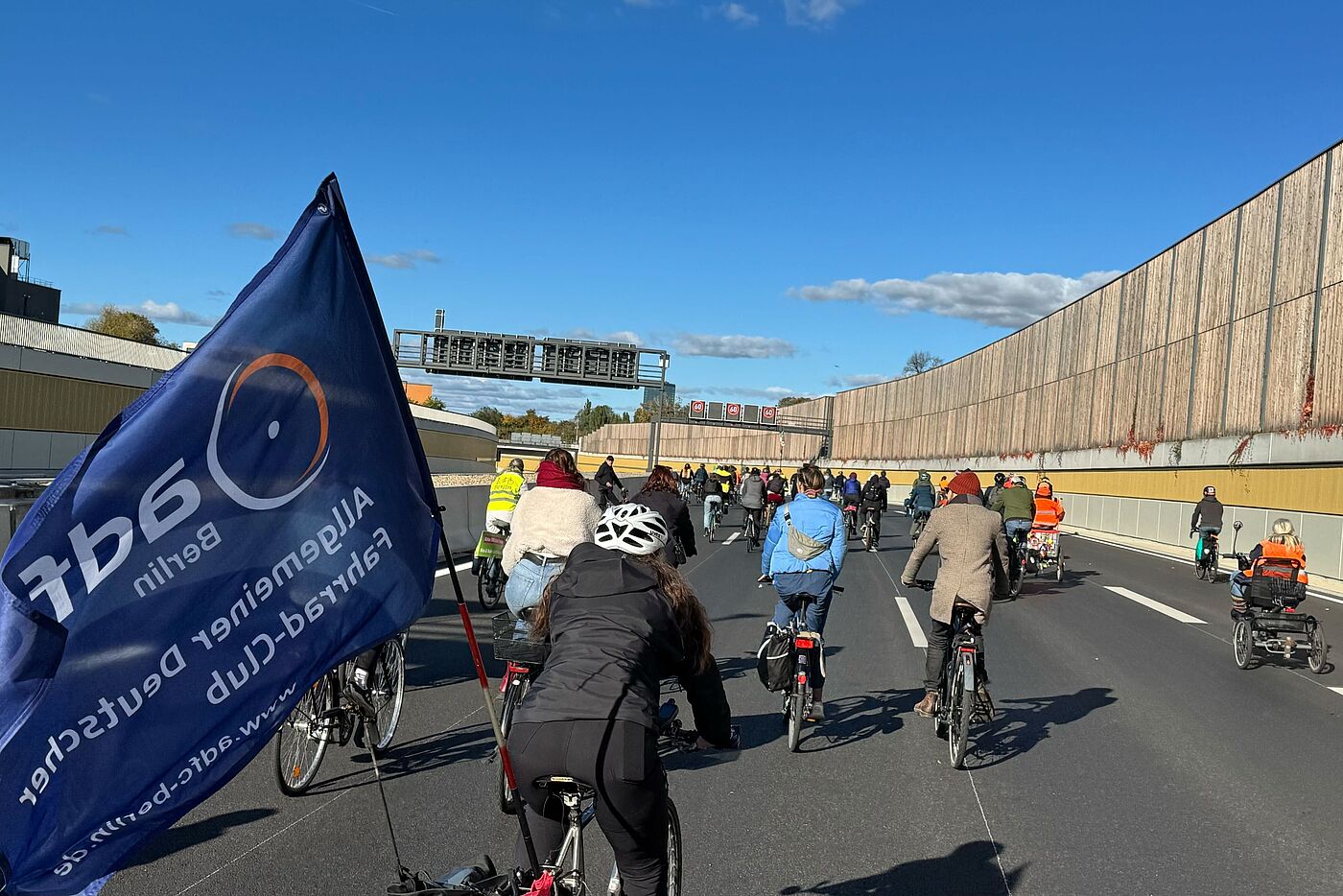 A100 Demo 18.10.2025 Radfahrende auf der Autobahn, blaue ADFC Fahne im Vordergrund