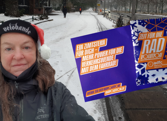 Die Fotomontage zeigt SuSanne Grittner auf der Seestraße mit einer Postkarte, an der eine lila und weiß bedruckte Plastikverpackung angeheftet ist.