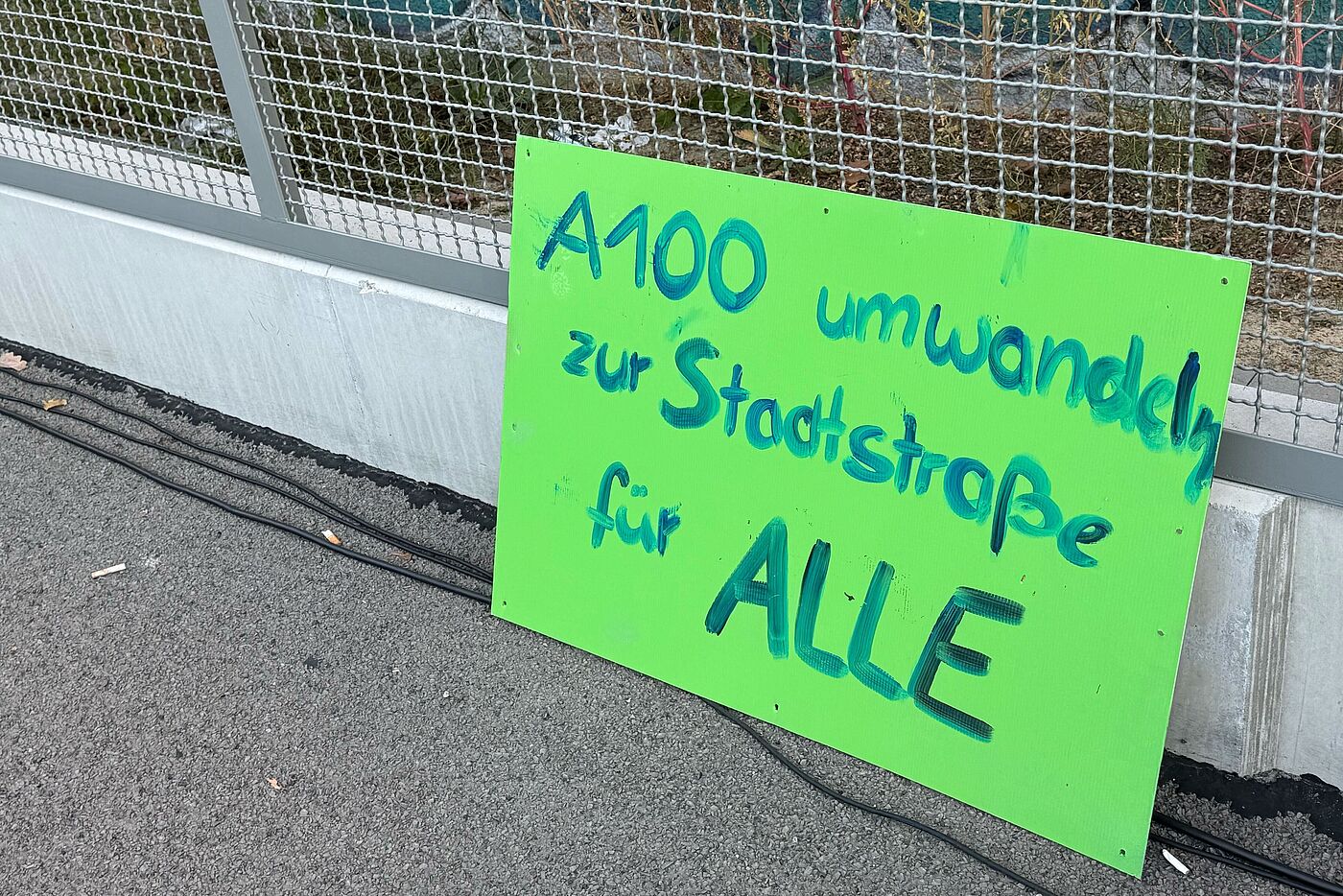 A100 Demo 18.10.2025 Grünes Schild auf dem steht: A100 umwandeln zur Stadtstraße für ALLE