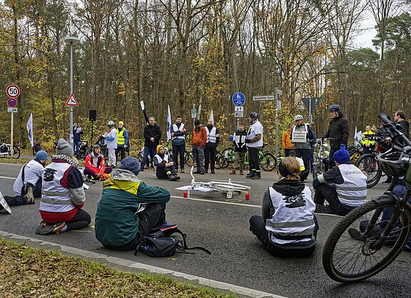 Menschen sitzen zur Mahnwache auf der Fahrbahn und gedenken eines getöteten Radfahrers