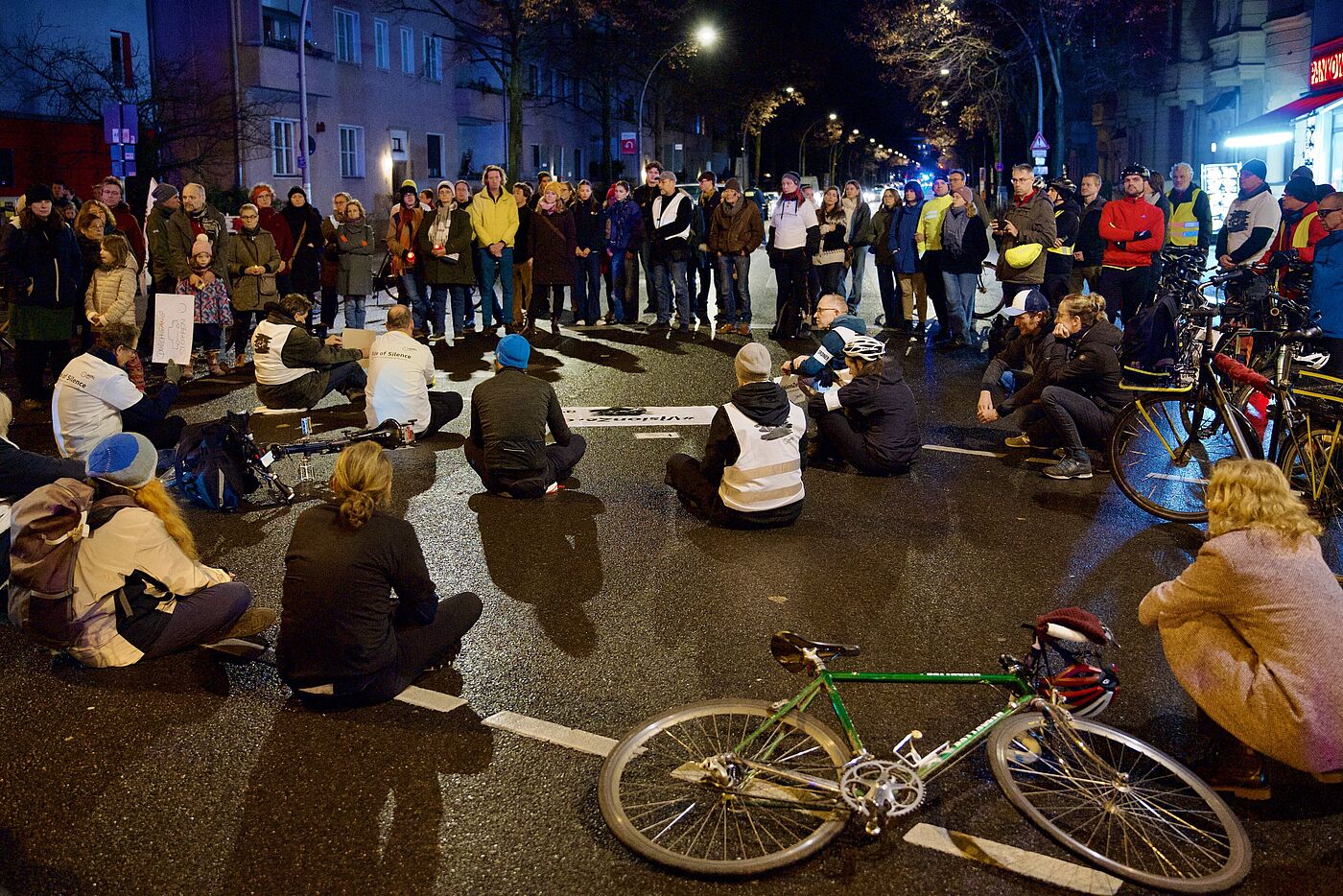 Meschen sitzen bei einer Mahnwache für einen getöteten Radfahrer auf der Straße