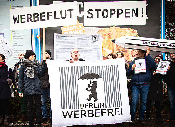 Menschen mit Plakaten und einem riesigen Stift: Start der Unterschriftensammlung von Berlin Werbefrei am 16. Januar 2018