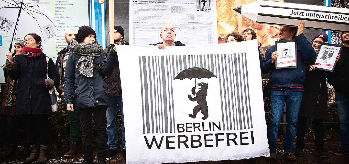 Menschen mit Plakaten und einem riesigen Stift: Start der Unterschriftensammlung von Berlin Werbefrei am 16. Januar 2018