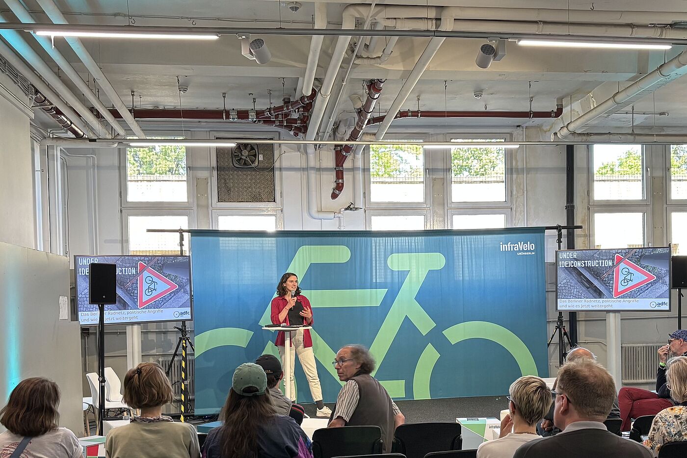 Frau hält einen Vortrag vor einem Fahrradbanner bei der VELO Messe