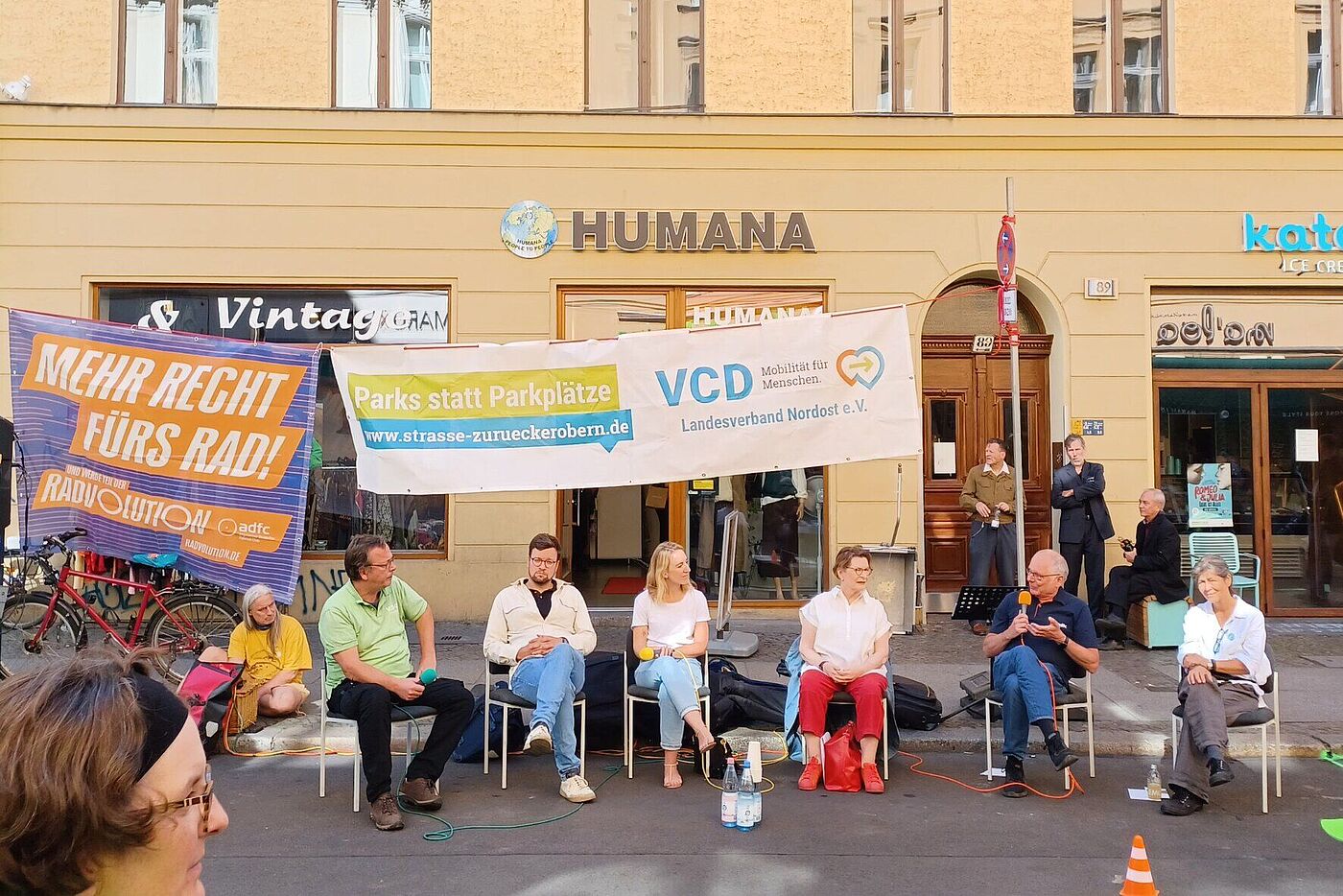 Menschen sitzen beim PARKing Day auf Stühlen auf der Straße bei einer Diskussion