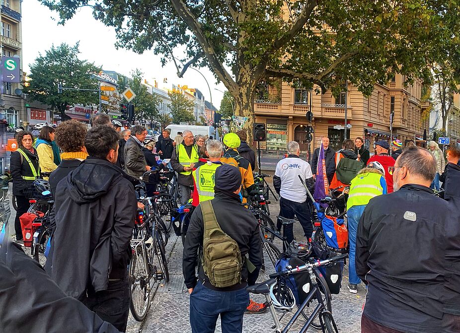 Rede auf dem Richard-von-Weizsäcker-Platz zum "Anradeln" der geschützten Radwege an der Schöneberger Hauptstraße Am Richard-von-Weizsäcker-Platz steht eine Gruppe Menschen, die die Einweihung der geschützten Radwege an der Hauptstraße feiern. Ein Vertreter der Senatsverwaltung und die Stadträtin des Bezirks Tempelhof-Schöneberg halten eine Rede