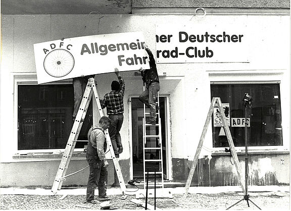 Männer hängen ein Allgemeiner Deutscher Fahrrad Club-Schild auf