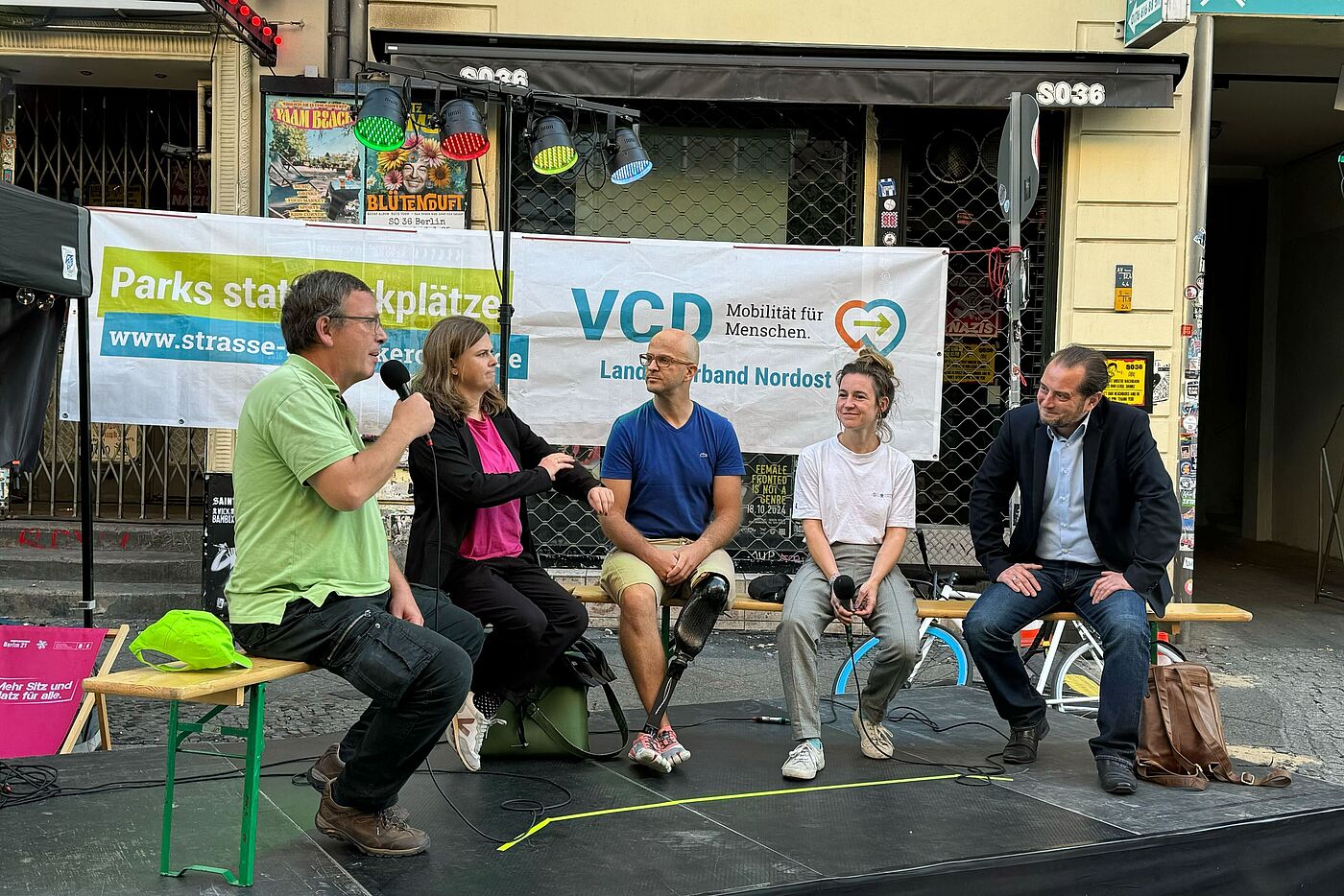 Fünf Menschen sitzen draußen bei einer Podiumdiskussion