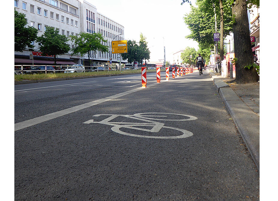 Mai 2024: Ein Stück neuer Radweg auf der Hauptstraße Richtung Richard-von-Weizsäckerplatz mit Protektion Zu sehen ist eine Fahrbahn. Ein Stück neuer Radweg auf der Hauptstraße Richtung Richard-von-Weizsäckerplatz wird von sogenannten Leitboys geschützt.