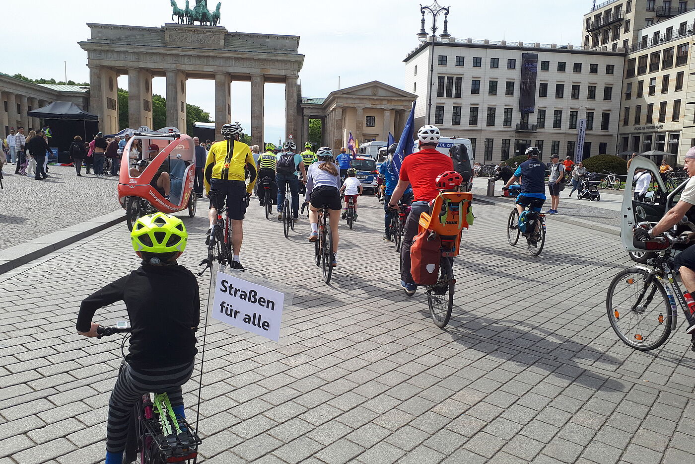 Kinder und Erwachsene fahren auf das Brandenburger Tor zu