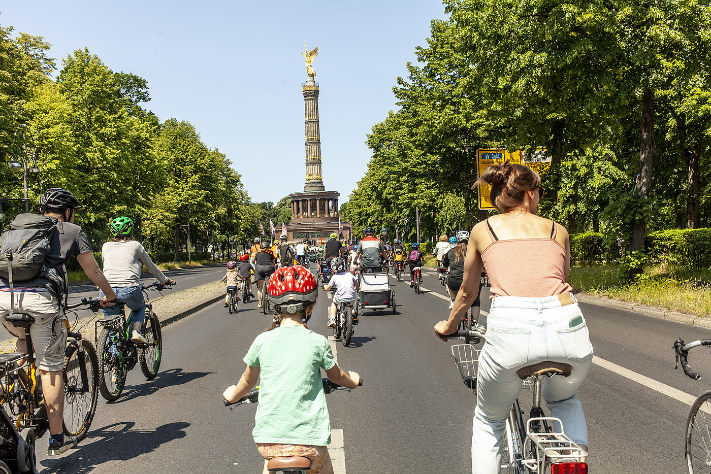 Kinder und Erwachsene auf Fahrrädern fahren auf die Siegessäule in Berlin zu