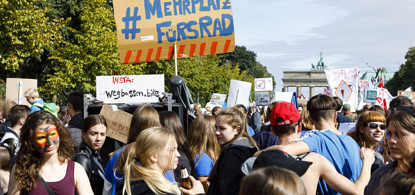 Teilnehmende halten bei einer Demo ein Schild hoch.