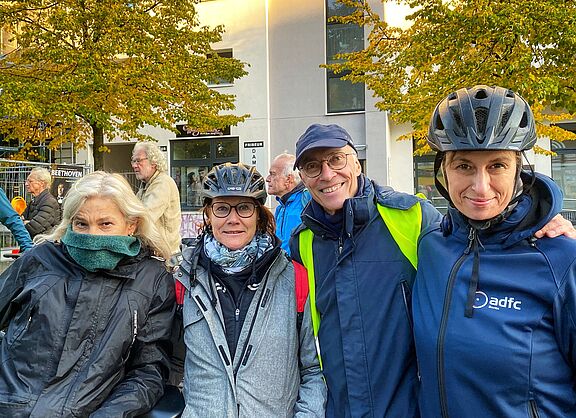 Vier Mitglieder des ADFC Schöneberg stehen in einer Gruppe auf dem Richard-von-Weizsäcker-Platz und lächeln in die Kamera. Sie sind zum "Anradeln" der geschützten Radwege an der Schöneberger Hauptstraße gekommen.