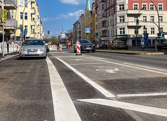 Baustelle und erste Markierungen für einen sicheren Radweg auf der Grunewaldstraße zwischen Goltzstraße und Martin-Luther-Straße. Auf der Fahrbahn sind Markierungen zu sehen, die den Radweg vom Autoverkehr abgrenzen.