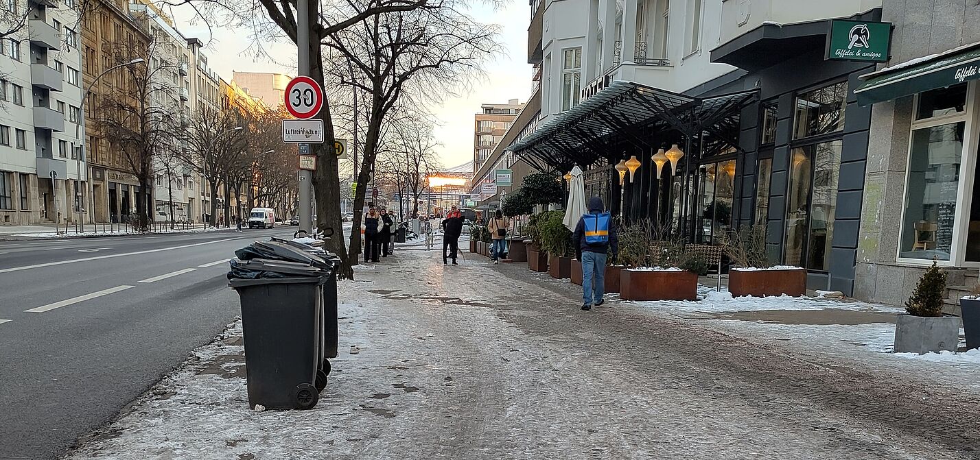 Im rechten Bereich ist ein vereister Gehweg und nicht erkennbar Radweg zu sehen, links davon ist Schnee- und Eis-freier Asphalt auf der Fahrbahn