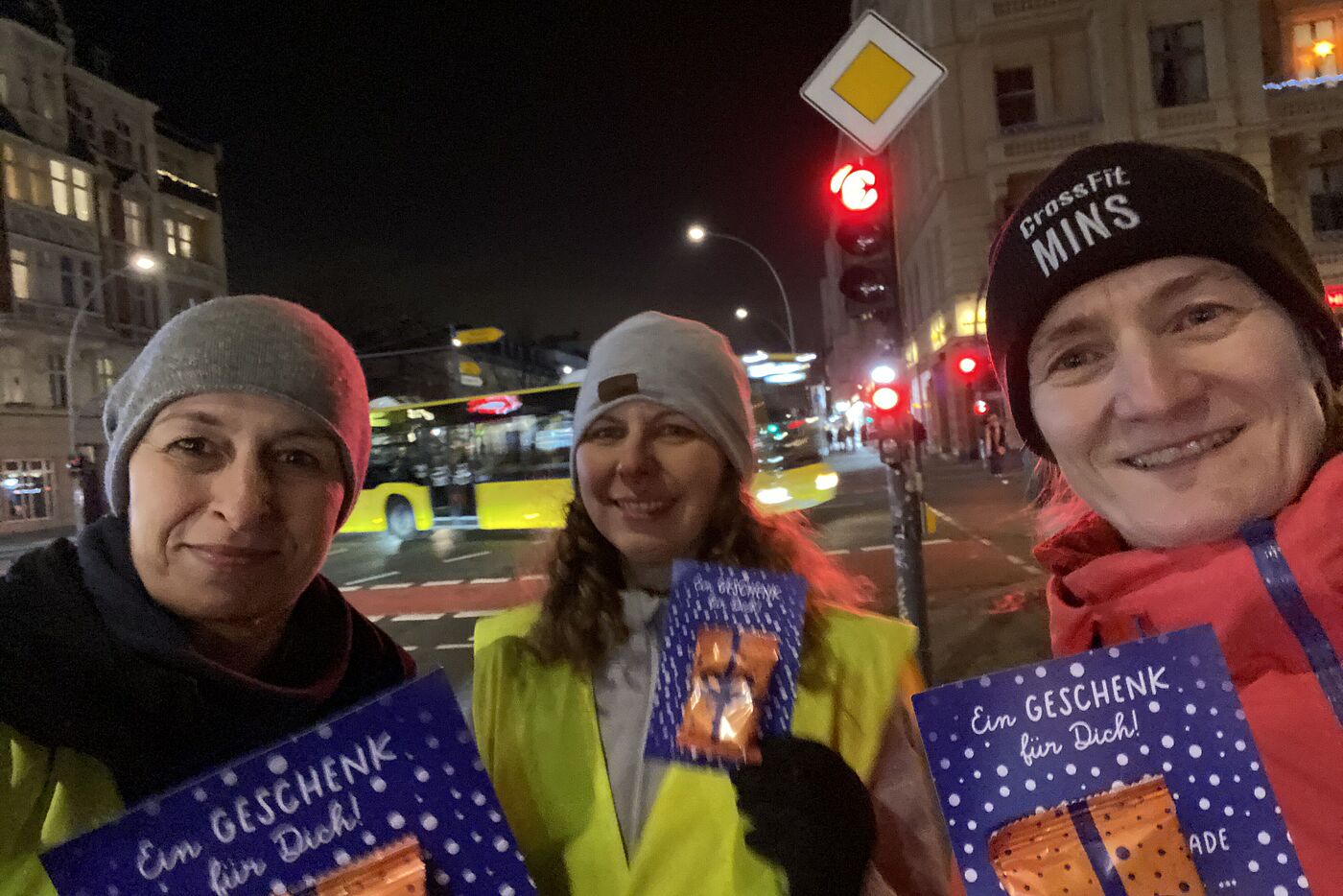 "Selfie" von drei Frauen, die an einer roten Ampel in Berlin Schöneberg stehen,  Hauptstraße Ecke Kolonnenstraße. Sie halten Karten des ADFC mit angehefteten Lebkuchen in den Händen.