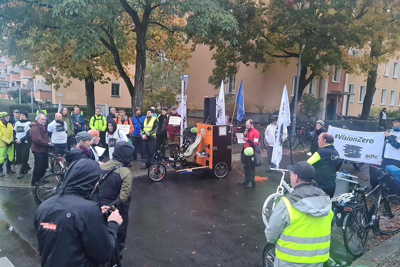 Menschen stehen bei einer Mahnwache auf der Straße, Vision Zero Banner