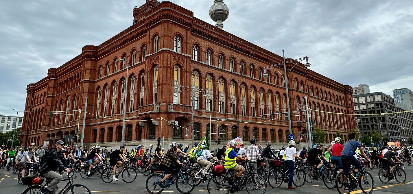 Menschen fahren bei einer Fahrrademonstration um das Rote Rathaus