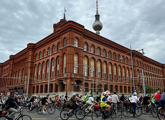 Menschen fahren bei einer Fahrrademonstration um das Rote Rathaus