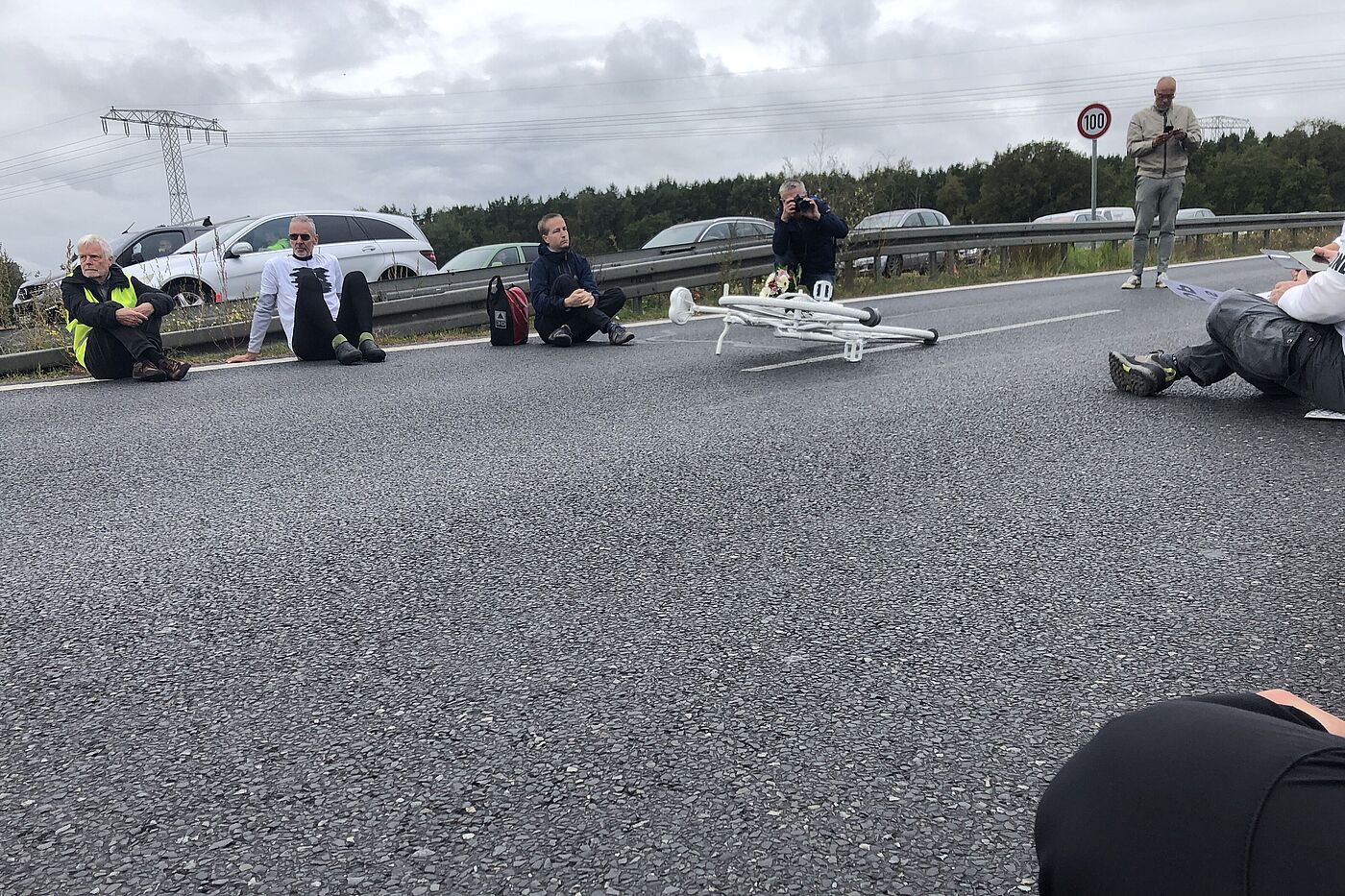 Geisterrad Oktober 2025 Kleinziethen Menschen sitzen bei einer Mahnwache um ein weißes Fahrrad auf der Straße