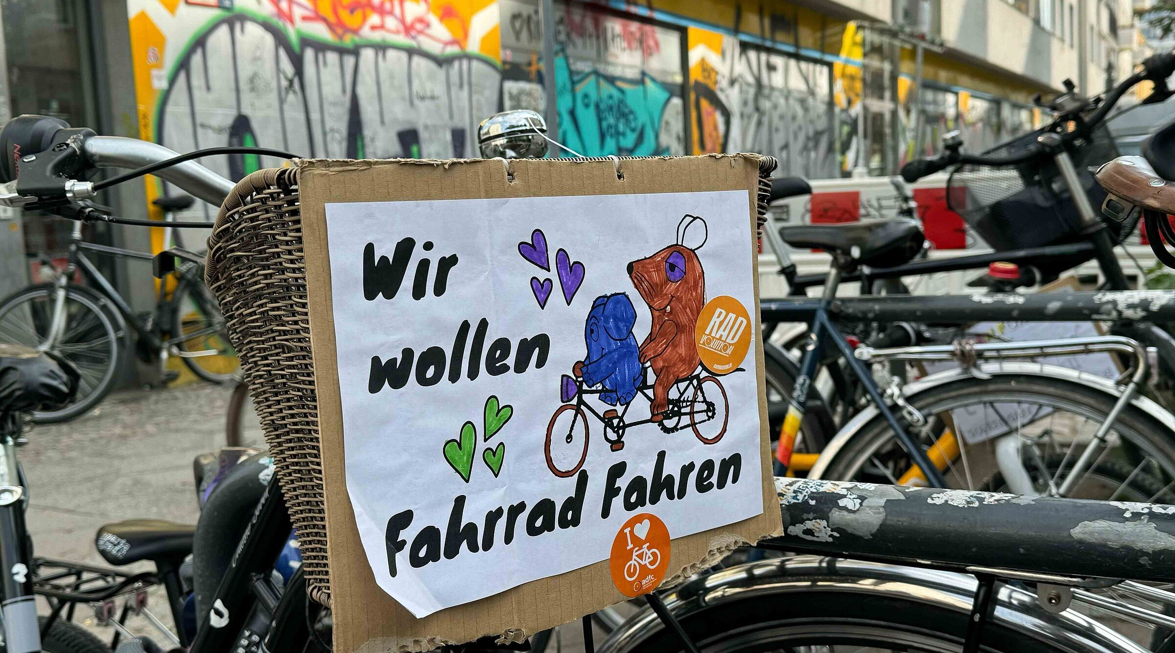 Selbstgemaltes Schild an Fahrrad mit der Maus und Elefanten auf dem steht: Wir wollen Fahrrad fahren