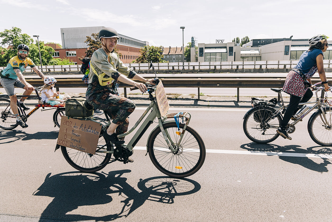 Radfahrende mit Mottoschild auf der Autobahn