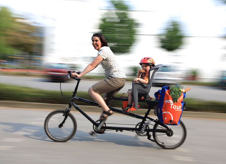 Eine Frau mit Kleinkind auf dem Rad Eine Frau mit Kleinkind auf dem Rad.