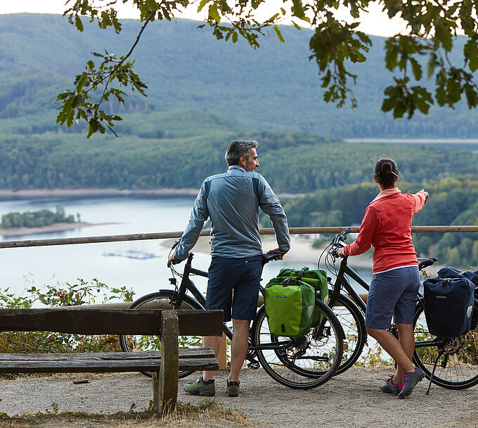 Radreisen Zwei Personen mit Fahrrad an einer Bank